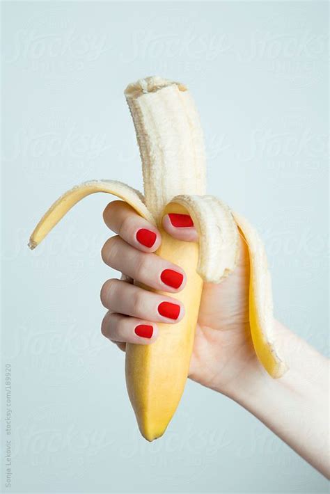 female hand holding a peeled biten banana photography color art photography