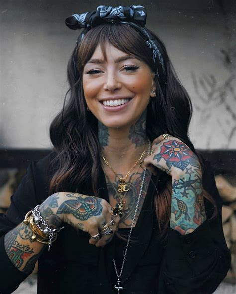 a woman with many tattoos on her arm and chest smiling at the camera