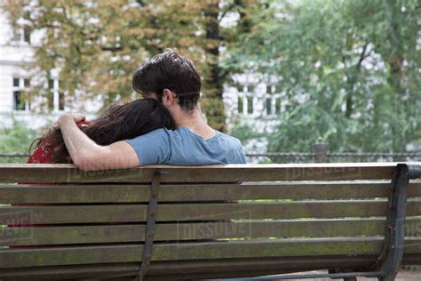 young couple sitting  park bench rear view stock photo dissolve