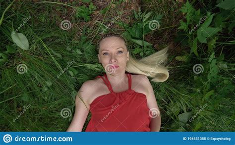 Woman Blonde Lies On The Ground In The Grass In A Red