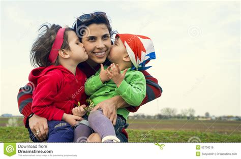 due bambine che baciano la loro madre fuori immagine stock