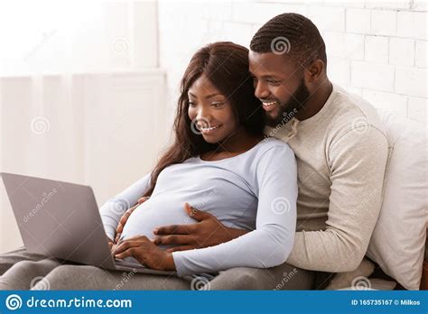 close up of black pregnant couple using laptop at home