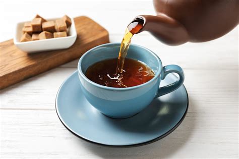 pouring black tea  ceramic cup  wooden table teacup wellness