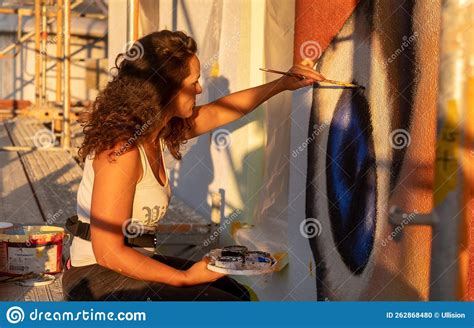 Female Artist Painter Woman With Curly Brunette Hair Paints A Street