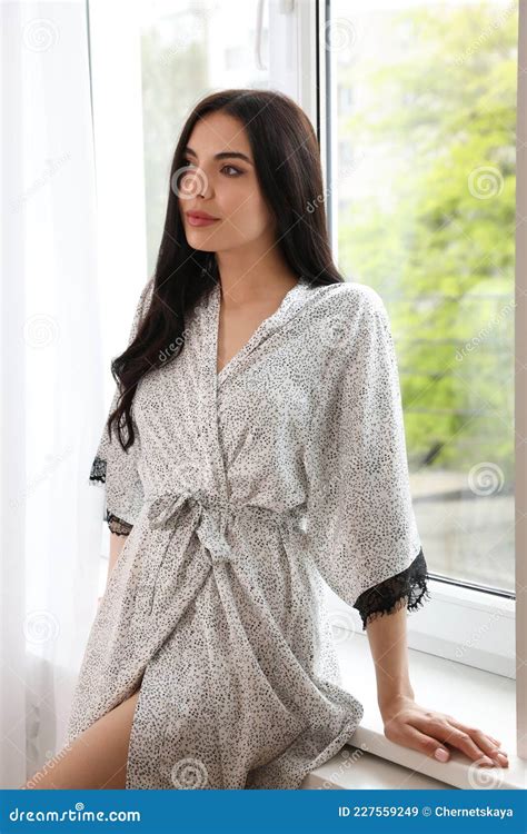Pretty Young Woman In Beautiful Silk Robe Near Window At Home Stock