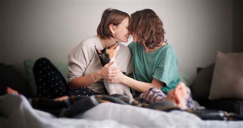 Beautiful Happy Lesbian Couple In Pajamas Sitting On Bed In The Morning