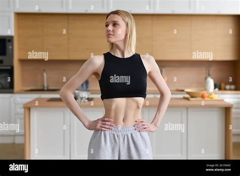 Skinny Woman Sucking In Her Belly And Standing In The Kitchen Stock