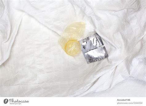 a open condom package on white sheets of a bed contraceptives a