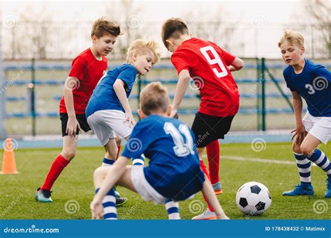 school boys playing football game young players kicking soccer ball  sports grass pitch stock