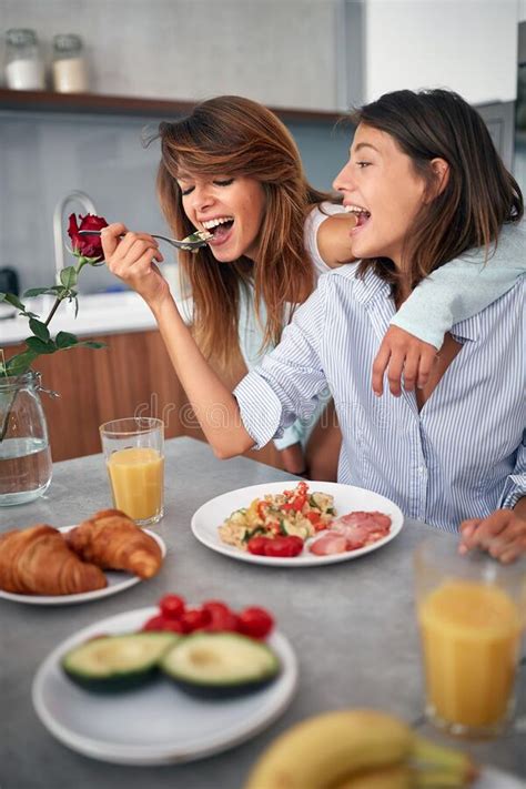 Smiling Gay Lasbian Couple At Morning In Kitchen Eating Breakfast Stock