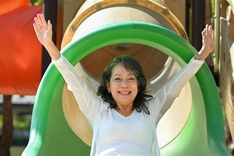 Overjoyed Mature Grandma Having Fun On Colorful Slide Happy Moment