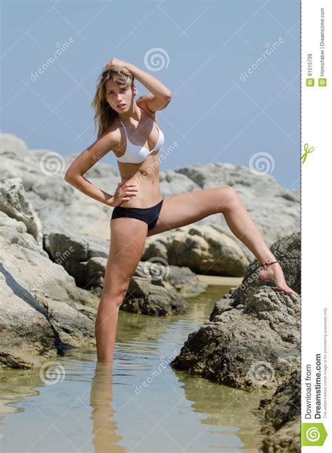 Model Standing Between Sea Rocks Wearing A Black And White