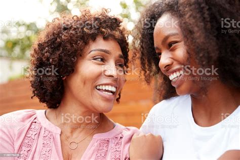Middle Aged Black Mum And Teen Daughter Smiling At Each Other Stock