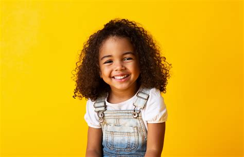 happy smiling african american child girl yellow background pediatric dental associates