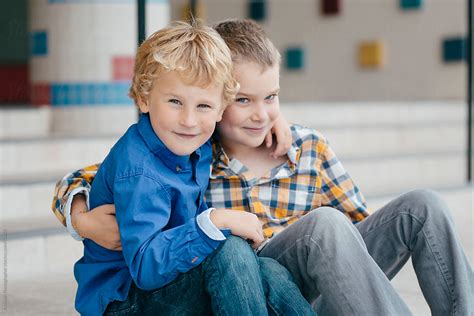 Two Happy Brothers Sitting On The Front Steps Of A School Looking At