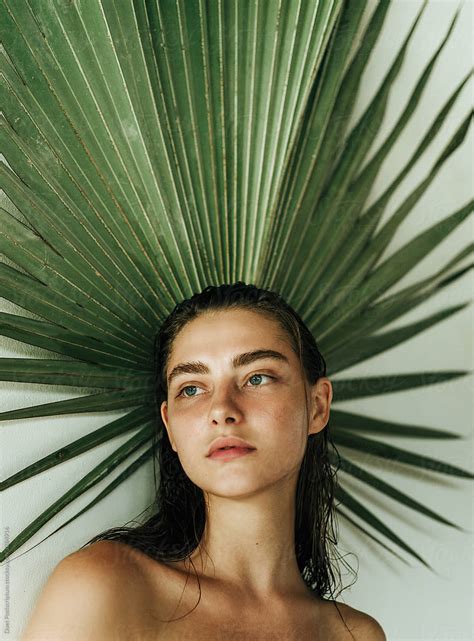 portrait of a beautiful girl on a background of palm leaf by stocksy