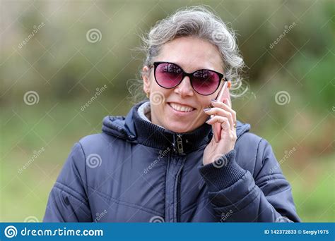 Woman In Sunglasses Talking On A Mobile Phone In The Forest Stock Image