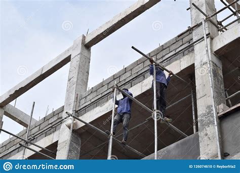 filipino construction workers installing metal pipe scaffolds on high rise building without