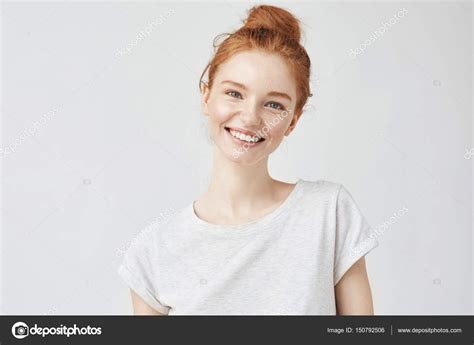 headshot portrait of happy ginger girl with freckles smiling looking at camera white background