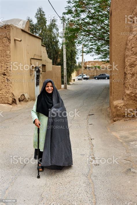 Muslim Elderly Woman Dressed In Black Chador On The Street Of Old Town