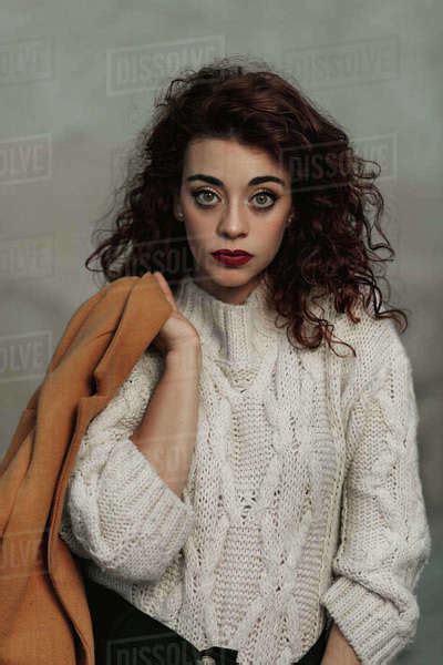 Curly Haired Brunette Female In Warm White Knitted Jumper Holding Beige