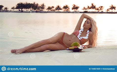 carefree blonde woman lying on white sand enjoying