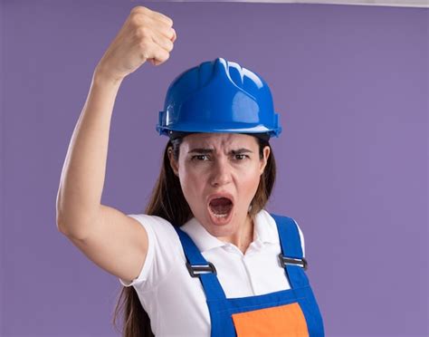 Возбужденная молодая женщина строитель в униформе поднимающая кулак
