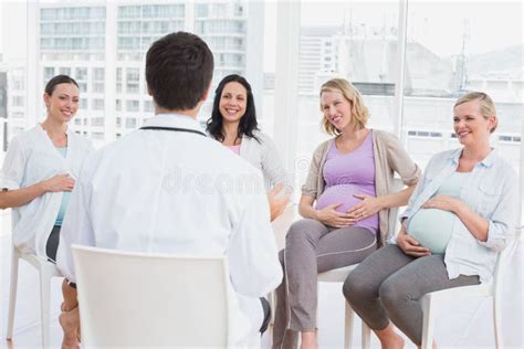 glimlachende zwangere vrouwen die aan arts bij prenatale klasse luisteren stock afbeelding