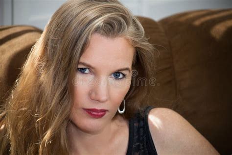 Closeup Portrait Mature Blonde Female Sitting On Sofa Looking Away From