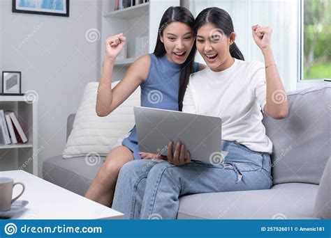 Asian Lesbian Couple Using Laptop In The Living Room Happily Raising