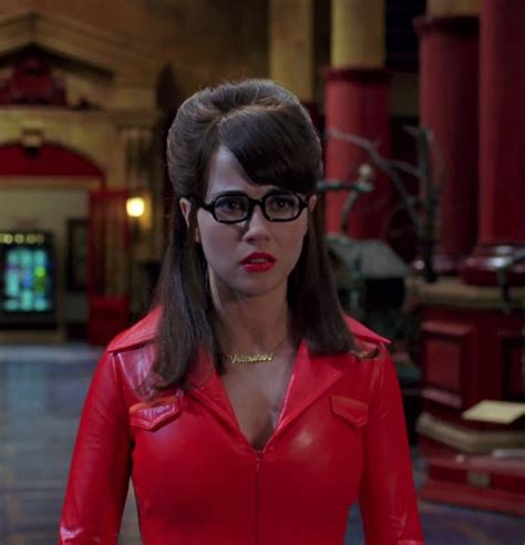 A Woman Wearing Glasses And A Red Leather Jacket In A Room With Columns