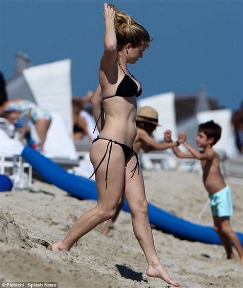 alice eve very nearly spills out of her black bikini on