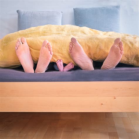 family   lying  bed showing feet  covered  yellow blanket  stock photo