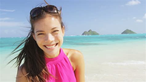 woman listening to music on smart phone using earphones in bikini on beach smiling happy