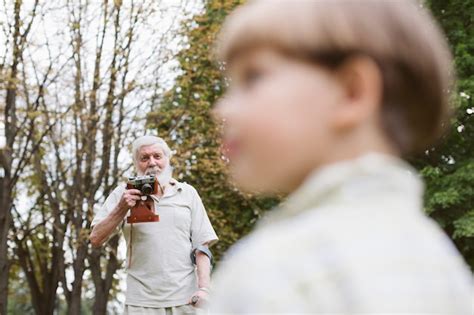 Free Photo Grandpa With Grandson In Park Taking Photos
