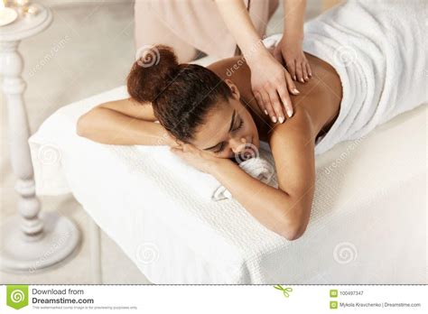 beautiful african girl smiling enjoying massage with closed eyes in spa