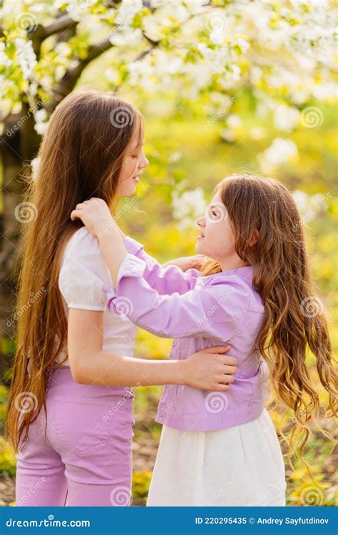 two girls sisters have fun and cuddle in the garden with flowering