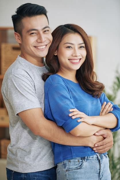 Free Photo Smiling Young Asian Couple Standing And Hugging Indoors