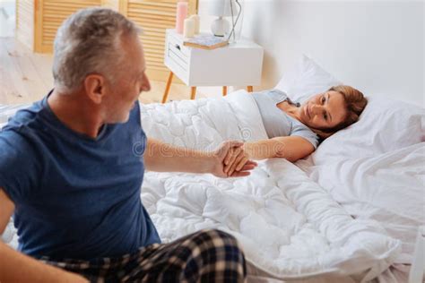 Grey Haired Husband Taking Hand Of His Wife After Waking Up Stock Image