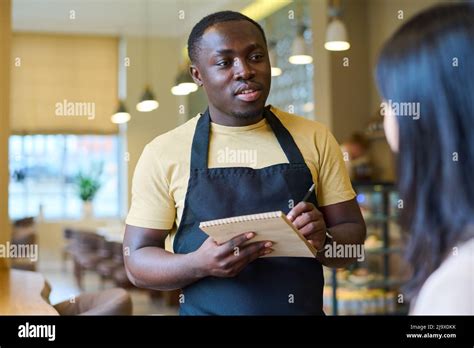 African American Waiter Making Notes In Notepad While Talking To Woman