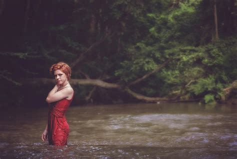 Woman In Red String Spaghetti Strap Dress On Body Of Water Near Forest