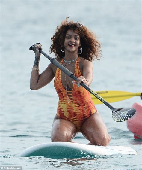 rihanna showcases her curves in a flame coloured swimsuit as she paddle