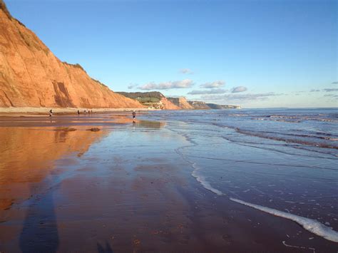 red cliffs reflecting   wet sand   tide sidmouth east devon