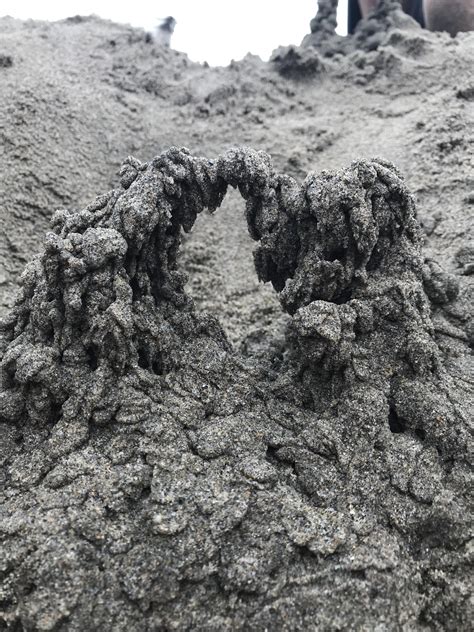 my little brother made an arch at the beach by dripping wet sand from