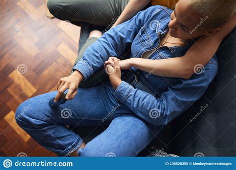 loving same sex female couple holding hands lying on sofa
