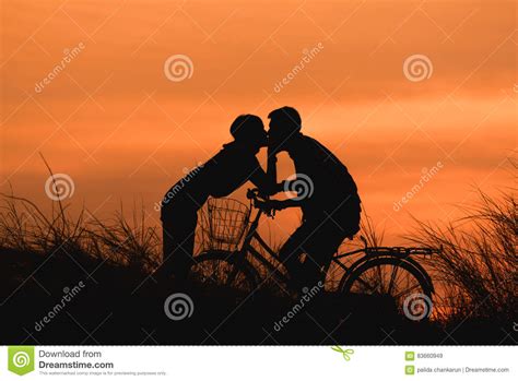Silhouette Couple Kissing On Bike Over Sunset Background