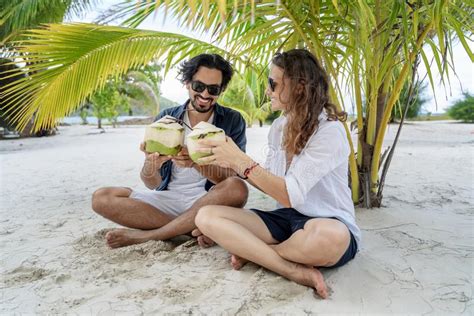 beach couple sitting on white sand beach on romantic travel honeymoon