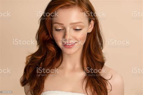 Young Woman Standing Wrapped In Towel Looking Down Beige Background