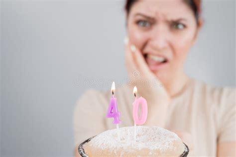 unhappy woman holding a cake with candles for her 40th birthday the