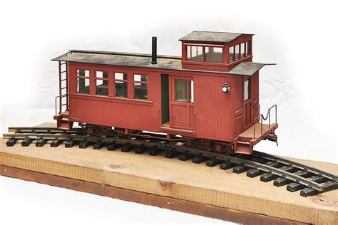 small red train car sitting  top   wooden rail road track  rails